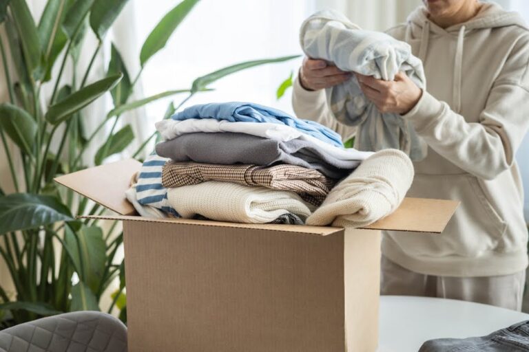 woman in a hoodie folding clothes to put in a box for donation